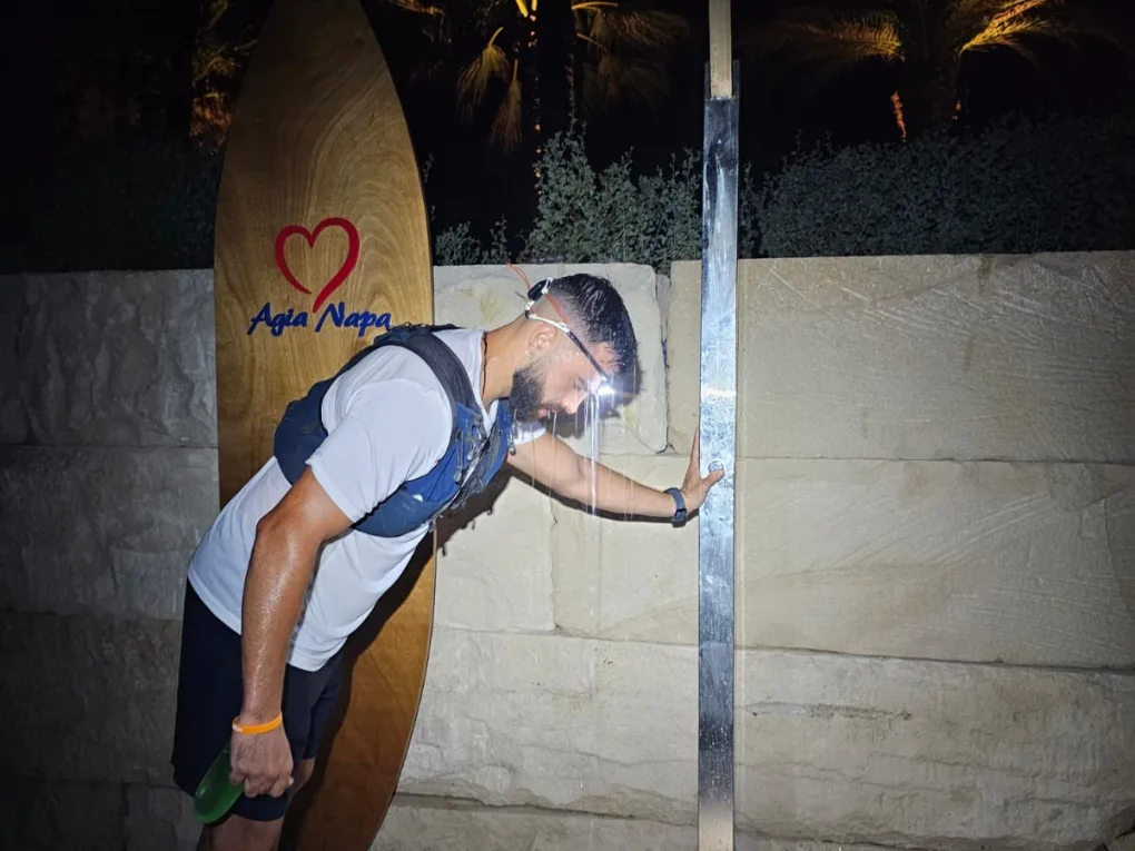 The athlete leaning on the Agia Napa surfboard monument at night, head down