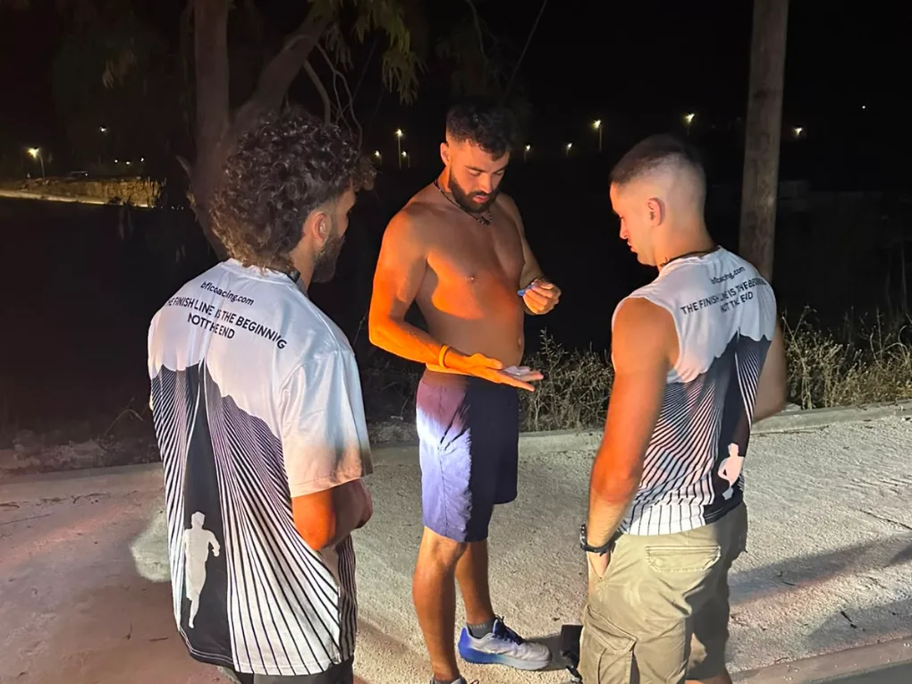 The athlete on a roadside at night with two crew members attending to him under a street light