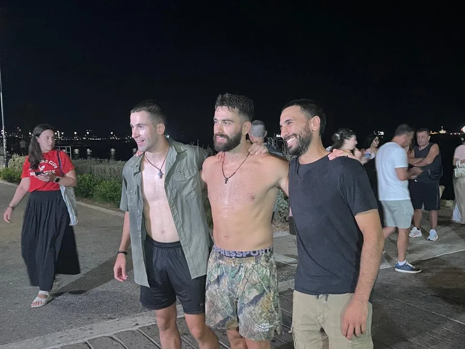A group of people on the Molos Pier boardwalk at night around the athlete